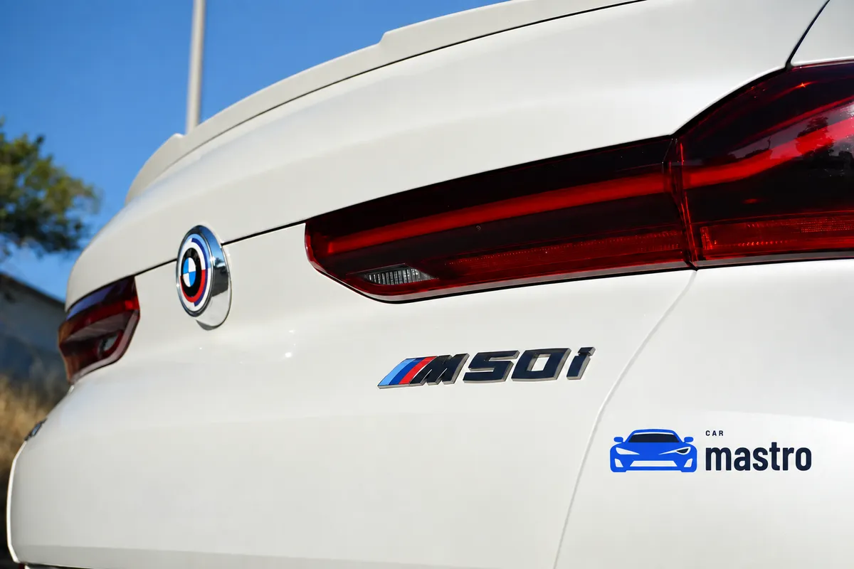 Rear detail of a white BMW X6 M50i, showing the BMW emblem, M50i badge and rear lights